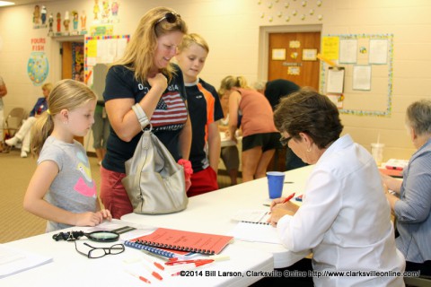 A mother checks in before casting her ballot as her two children watch