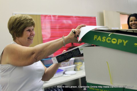 Joan Burke, a volunteer at the Teachers Warehouse grabs the first pack of the donated paper for Tonya Campbell, a sixth grade teacher at Richview Middle School.