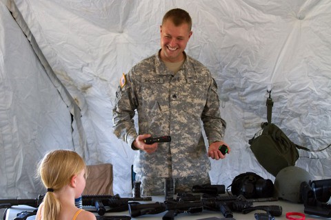 Sgt. Nickolas Ehrhardt, the Fort Campbell Special Reaction Reaction Team NCO in charge, demonstrates a stun gun to MacKenzie, 6, during a back-to-school bash Aug. 2, at West Creek Elementary School in Clarksville, Tenn. He was one of several volunteers from the battalion who assisted with the event. (Sgt. Leejay Lockhart, 101st Sustainment Brigade Public Affairs)