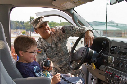 Spc. Damaris Gonzalez, a military volunteer and member of Fort Campbell's Special Reaction Team, lets Elijah, 8, control the lights and sirens on the SRT’s truck during a back-to-school bash Aug. 2, at West Creek Elementary School in Clarksville, Tenn. Soldiers have assisted the school as volunteers since it opened seven years ago. (Sgt. Leejay Lockhart, 101st Sustainment Brigade Public Affairs)