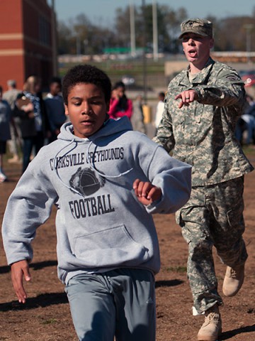 Spc. Shea Hogsed, a Military Police Soldier with the 551st Military Police Company, 716th Military Police Battalion, 16th Military Police Brigade, supported by the 101st Sustainment Brigade, 101st Airborne Division, cheers on Trey, a student at West Creek Middle School, on an obstacle course the MPs had set up for the students Nov. 7 at West Creek Middle School in Clarksville, Tenn. (U.S. Army photo by Sgt. Leejay Lockhart)