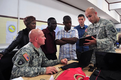 Chief Warrant Officer 2 Angel Mitre, right, the Joint Forces Command – United Assistance liaison officer to the National Ebola Crisis Center, Monrovia, explains to personnel from the Liberian Institute of Statistics – Geo-Information Services how an exchange of geospatial data between the JFC-UA and LISGIS created a more robust, useful product for organizations supporting Operation United Assistance, Oct. 29, 2014. (Sgt. 1st Class Nathan Hoskins)