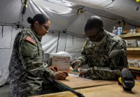 Spc. Brandon Carr, right, native of Kinston, North Carolina, and postal specialist for the 18th Human Resources Company, 82nd Special Troops Battalion, 82nd Sustainment Brigade, gives his ‘stamp of approval’ on a package that Spc. Savannah Martinez, left, native of Corpus Christi, Texas, and ammunition specialist for the 101st Sustainment Brigade, is sending home to her family in the now fully operational post office at Roberts International Airport, Monrovia, Liberia, Dec. 22, 014. The post office at RIA is the first fully functional Army post office to open in Liberia, allowing Soldiers deployed to there as part of Joint Forces Command – United Assistance to buy flat rate boxes, apply postage and send their own care packages back home to their family and friends in the U.S. Operation United Assistance is a Department of Defense operation in Liberia to provide logistics, training and engineering support to U.S. Agency for International Development-led efforts to contain the Ebola virus outbreak in western Africa. (Spc. Caitlyn Byrne/U.S. Army)