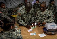 Spc. Guadalupe Shim, left, native of Dallas, and Spec. Brandon Carr, native of Kinston, N.C., right, both postal specialists for the 18th Human Resources Company, 82nd Special Troops Battalion, 82nd Sustainment Brigade, assist Spec. Randritz Hopper, center, native of Shelby, N.C., and medical logistics specialist for the 583rd Medical Logistics Company, 1st Medical Brigade with a package that he is sending back to the U.S. from Roberts International Airport, Monrovia, Liberia, on Dec. 22, 2014. The post office at Roberts International Airport is the first fully functional Army post office to open in Liberia, allowing Soldiers deployed to Liberia in support of Joint Forces Command – United Assistance to buy flat rate boxes, apply postage and send their own care packages back home to their family and friends in the states. Operation United Assistance is a Department of Defense operation in Liberia to provide logistics, training and engineering support to U.S. Agency for International Development-led efforts to contain the Ebola virus outbreak in western Africa. (Spc. Caitlyn Byrne/U.S. Army)