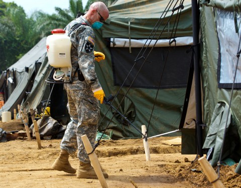 Capt. Scott Mueller, executive officer, 61st Preventative Medicine Detachment, 86th Combat Support Hospital, Fort Campbell, Ky., sprays insecticide around the tents of engineers currently building a health clinic in Gbediah, Liberia (Sgt. Matt Britton/U.S. Army)