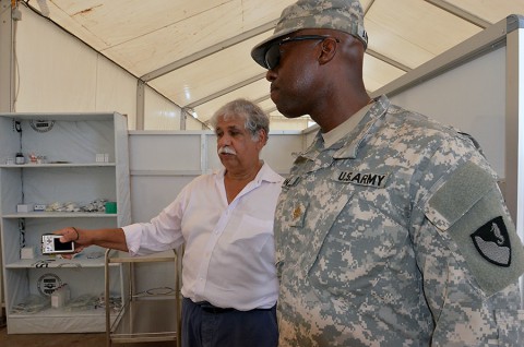 Dario Gonzalez, left, a medical director with the International Organization for Migration and a native of New York City, explains to Maj. Uzoma Aniniba, a Denver native, and the operations officer for the 36th Engineer Brigade, how the health care workers will archive the patients records electronically, after the grand opening ceremony of the Ebola treatment unit near Buchanan, Liberia, Dec. 22, 2014, as part of Operation United Assistance.  (Sgt. Ange Desinor 13th Public Affairs Detachment)