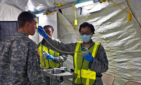 First Lt. Dan Thueneman, left, executive officer, Intelligence and Sustainment Company, Headquarters and Headquarters Battalion, 101st Airborne Division (Air Assault), fills out the signs and symptoms checklist before he has his temperature taken during his 21-day controlled monitoring period at Joint Base Langley – Eustis, Va., Jan. 20, 2015. (U.S. Army photo by Sgt. Matt Britton 27th Public Affairs Detachment/Released)