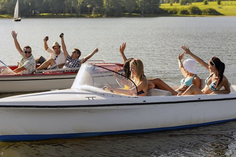 Waving friends sitting in motorboats enjoying the summer time.