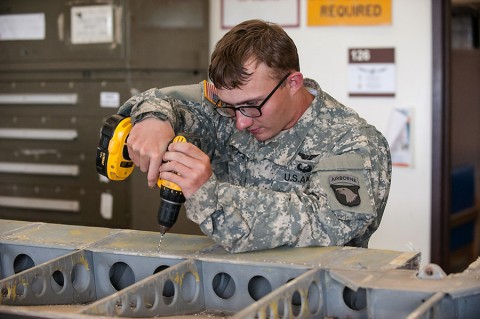 Pfc. Jacob Capps, an airframe structural repair specialist with Company B, 96th Aviation Support Battalion, 101st Combat Aviation Brigade, 101st Airborne Division, drills to enlarge holes in the metal of an aileron of a C-47 Skytrain, here, May 18, 2015. Sheet metal will replace canvas, and drilling the holes ensure that the replacement rivets will fit properly when installed. (Sgt. Duncan Brennan, 101st CAB, 101st Airborne Division (Air Assault) Public Affairs)