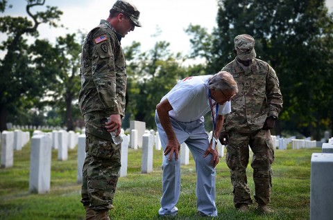 Staff Sgt. David Payton, the 101st Airborne Division NCO of the year; Jim Devasher, a U.S. Marine Corps veteran from Bowling Green, Ky.; and Sgt. Macharia Webster, the 101st Airborne Division Soldier of the year, stop to read a tombstone in the Arlington National Cemetery in Washington, July 25, 2015. The Arlington National Cemetery was the final stop during the Screaming Eagle Honor Flight. (Staff Sgt. Sierra A. Fown, 2nd Brigade Combat Team, 101st Airborne Division (Air Assault) Public Affairs)