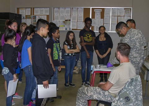 Pfc. Michael Herrera, a medic, and Sgt. 1st Class Glenn Riddell, an operations sergeant, both with the 218th Military Police Company, 716th Military Police Battalion, 101st Sustainment Brigade, 101st Airborne Division, demonstrate buddy aid during a visit to Fort Campbell, Ky., from the honor roll students of Clarksville’s West Creek Middle School May 15, 2015. (Sgt. 1st Class Mary Rose Mittlesteadt, 101st Sustainment Brigade, 101st Airborne Division (Air Assault) Public Affairs)