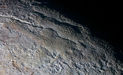 In this extended color image of Pluto taken by NASA’s New Horizons spacecraft, rounded and bizarrely textured mountains, informally named the Tartarus Dorsa, rise up along Pluto’s day-night terminator and show intricate but puzzling patterns of blue-gray ridges and reddish material in between. This view, roughly 330 miles (530 kilometers) across, combines blue, red and infrared images taken by the Ralph/Multispectral Visual Imaging Camera (MVIC) on July 14, 2015, and resolves details and colors on scales as small as 0.8 miles (1.3 kilometers). (NASA/JHUAPL/SWRI)