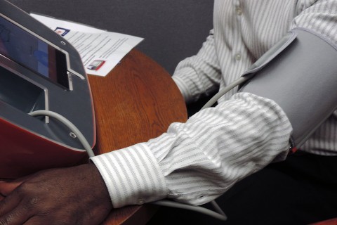 A man checking his blood pressure at an office kiosk. (American Heart Association)