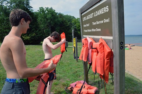 Two young swimmers place life vests from the Life Jacket Loaner board at the Cheatham Dam beach area in Ashland City, Tennessee. (Mark Rankin, U.S. Army Corps of Engineers, Nashville District)