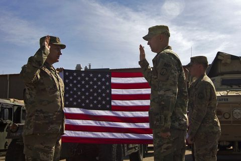 Col. Doyle Lassitter, commander for Distribution Management Center, Army Sustainment Command, stands in front of the United States flag along with his son, Cpl. Matthew Lassitter, as he re-enlists his son for four more years in the U.S. Army on Fort Campbell, Ky., April 18, 2016. (Sgt. Neysa Canfield, 101st Sustainment Brigade, 101st Airborne Division (AA) Public Affairs)