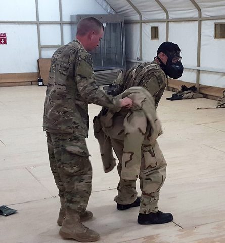 Capt. Matt McDuffie, left, Task Force Strike chemical, biological, radiological, and nuclear (CBRN) officer, demonstrates with a Soldier from Task Force Strike the proper Joint Service Lightweight Integrated Suit Technology removal at a training and logistical camp in southwest Asia, May 11, 2016. (1st Lt. Daniel I. Johnson)