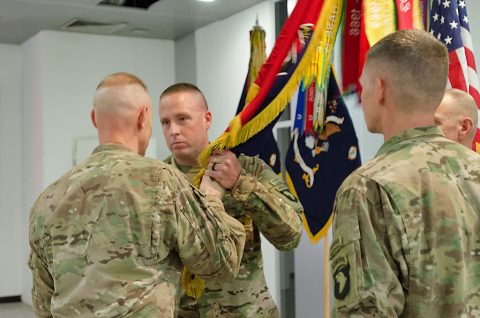 Col. Brett G. Sylvia, commander, 2nd Brigade Combat Team, 101st Airborne Division (Air Assault), passes the unit’s colors to Command Sgt. Maj. John L. Wilson, incoming brigade command sergeant major, during a change of responsibility ceremony held July 23, in Erbil, Iraq. (Staff Sgt. Peter J. Berardi) 