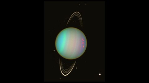 Uranus is seen in this false-color view from NASA's Hubble Space Telescope from August 2003. The brightness of the planet's faint rings and dark moons has been enhanced for visibility. (NASA/Erich Karkoschka (Univ. Arizona))