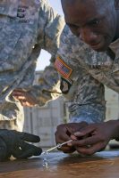 Capt. Abdoul R. Kane, commander for Headquarters and Headquarters Company, 101st Special Troops Battalion, 101st Airborne Division (Air Assault) Sustainment Brigade, 101st Abn. Div., attempts to place a third hex nut on a stack with a chopstick, Nov. 9, 2016, during the Command Team Physical Training Challenge at the 74th Composite Transportation Company motor pool on Fort Campbell, Ky. (Sgt. Neysa Canfield/101st Airborne Division Sustainment Brigade Public Affairs)