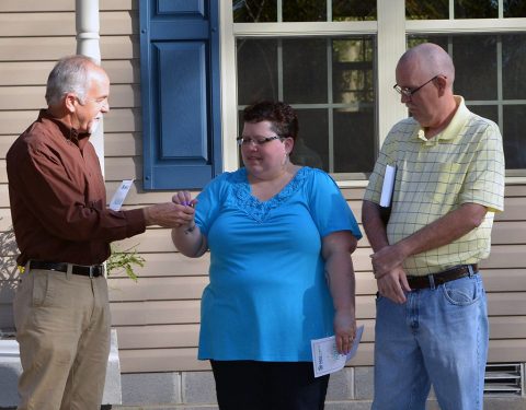 Rick Catignani, Board President, presents Susan Grasty with a new Bible and Herb Baggett, Founder and Board Member, presented the family with the keys to their new home. Rick Catignani, Board President, presents Susan Grasty with a new Bible and Herb Baggett, Founder and Board Member, presented the family with the keys to their new home.