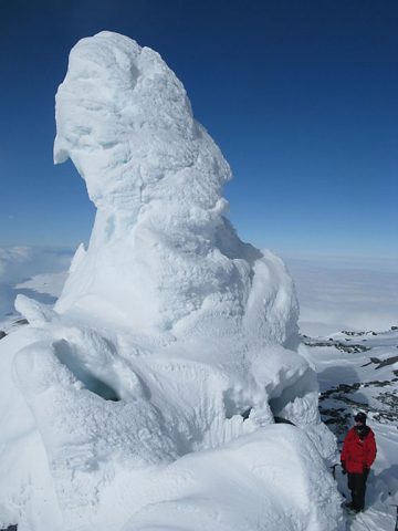 Aaron Curtis, a postdoctoral scholar at JPL, stands next to an ice tower. These towers form over caves as gases escape and freeze in the open air. (Nial Peters)