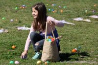 A girl filling up her bag with Easter eggs.