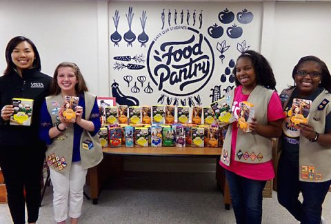 Belina Sengmanyvog, AmeriCorps VISTA, accepts a donation from Girl Scout Troop 2604 members Alaina Chandler, Jasmine Palmer and Jaylen Palmer.