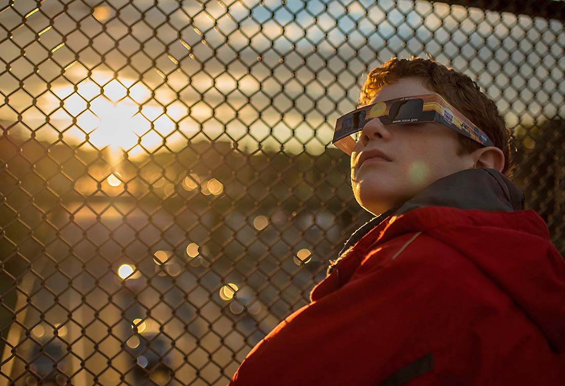 A boy wearing protective viewing glasses watches a partial solar eclipse from Arlington, Virginia, in 2014. (NASA/Bill Ingalls)