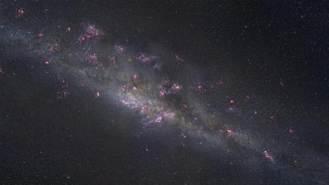 This artist's illustration portrays what the gravitationally lensed galaxy SDSS J1110+6459 might look like up close. A sea of young, blue stars is streaked with dark dust lanes and studded with bright pink patches that mark sites of star formation. The patches' signature glow comes from ionized hydrogen, like we see in the Orion Nebula in our own galaxy. (NASA, ESA, and Z. Levay (STScI))