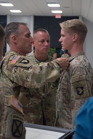 Lt. Col. Kurt Smith, commander 2nd Bn. 506th Inf. Regt., and Command Sgt. Maj. Thomas Conn, senior enlisted advisor, 2nd Bn. 506th Inf. Regt. pin Richard M. McErlean III, 14 with his Commander’s Award for Public Service, and make him an Honorary Member of the Regiment. McErlean III was made an Honorary Member of the Regiment after his service to the regiment. (Spc. Patrick Kirby. 40th Public Affairs Detachment) 