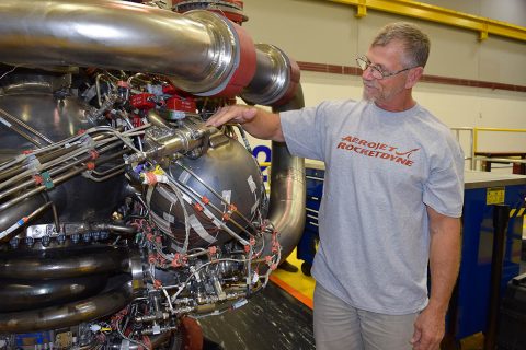 Owen Brayson, an instrumentation technician for NASA's RS-25 prime contractor Aerojet Rocketdyne, exhibits the pogo accumulator assembly, NASA's largest 3-D-printed rocket engine component tested in the restart of RS-25 production, on Engine 0528. The engine was successfully tested Dec. 13. (Aerojet Rocketdyne)