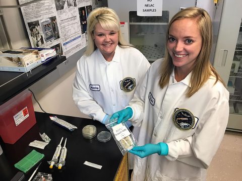Sarah Wallace (L), NASA microbiologist and Genes in Space-3 principal investigator, and Sarah Stahl (R), microbiologist, are seen in their Johnson Space Center lab with the in-flight sample from the Genes in Space-3 investigation. (Rachel Barry) Sarah Wallace (L), NASA microbiologist and Genes in Space-3 principal investigator, and Sarah Stahl (R), microbiologist, are seen in their Johnson Space Center lab with the in-flight sample from the Genes in Space-3 investigation. (Rachel Barry)