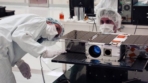 Electrical Test Engineer Esha Murty (left) and Integration and Test Lead Cody Colley (right) prepare the ASTERIA spacecraft for mass properties measurements in April 2017 prior to spacecraft delivery. (NASA/JPL-Caltech)