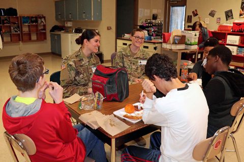 Blanchfield Army Community Hospital Soldiers, Capt. Lilly Vanek and Capt. Breanna Price talk with students from Northeast Middle School during lunch, Feb. 14. Soldiers and civilians from Blanchfield volunteer at the middle school through the Partners in Education program. Partners in Education works to unite schools with local businesses and organizations for the benefit of the entire community. (U.S. Army photo by Maria Yager)