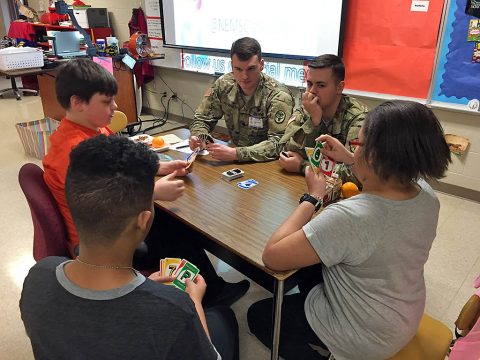 Blanchfield Army Community Hospital Soldiers, Spc. Jordan O'Brien and Spc. Jonathan Sluus play a card game with students from Northeast Middle School at lunch, Feb. 14. Soldiers and civilians from Blanchfield volunteer at the school through the Partners in Education program. Partners in Education works to unite schools with local businesses and organizations for the benefit of the entire community. (U.S. Army photo by Maria Yager)