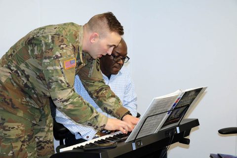 Spc. Walter Reuter, a pianist with the 101st Airborne Division Band, shows Fort Campbell Warrior Transition Battalion Soldier Chief Warrant Officer 3 Jonathan Dobey how to play a section of music on the keyboard. Dobey played music before injuring his shoulder in the line of duty and participates in a music class sponsored by the WTB's Occupational Therapy department as he recovers. (U.S. Army photo by Maria Yager)