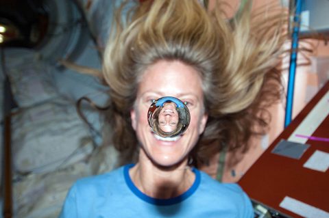 NASA astronaut Karen Nyberg watches a water bubble float freely between her and the camera, showing her image refracted in the droplet. (NASA)