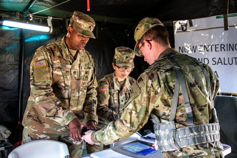 Staff Sergeant Arthur Cole III and Spc. Jihye Shim, trombonists from the 101st Airborne Division Band, recently check the credentials of Spc. William Hutchinson, 101st Main Command Post-Operational Detachment, Kentucky National Guard, and secures his cellphone before allowing him entry into a secure division area, during the Warfighter 18-3 exercise. (Staff Sgt. Todd Pouliot, 40th Public Affairs Detachment)