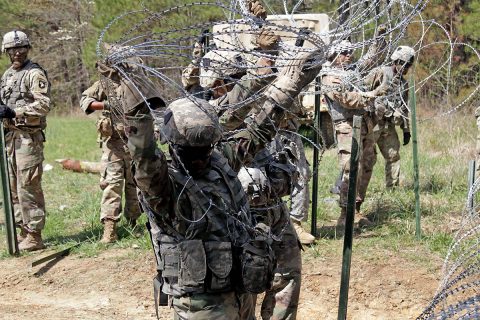 Pfc. Jennie Joy from 2nd Platoon and other soldiers from 2nd Platoon, Alpha Company, 39th Brigade Engineer Battalion, 2nd Brigade Combat Team, 101st Airborne Division (Air Assault), lifts concertina wire to install it into an Eleven-Row Obstacle, April 18th on Fort Campbell, KY. The Eleven-Row obstacle was constructed during the platoon’s weekly counter-mobility, mobility and survivability training. (U.S. Army photo by Pfc. Beverly Roxane Mejia, 40th Public Affairs Detachment) 