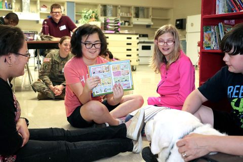 After reading the text, a Northeast Middle School student shows therapy dog Samson pictures from a book. Blanchfield Army Community Hospital pathology technician and animal assisted therapy volunteer Angela Barnett brought her therapy dog Samson to a recent visit with the hospital's Partners in Education school recently. Students took turns reading stories to Samson and learned about the differences between a service dog and a therapy dog. (U.S. Army photo by Maria Yager)