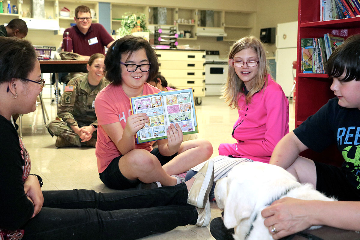After reading the text, a Northeast Middle School student shows therapy dog Samson pictures from a book. Blanchfield Army Community Hospital pathology technician and animal assisted therapy volunteer Angela Barnett brought her therapy dog Samson to a recent visit with the hospital's Partners in Education school recently. Students took turns reading stories to Samson and learned about the differences between a service dog and a therapy dog. (U.S. Army photo by Maria Yager)