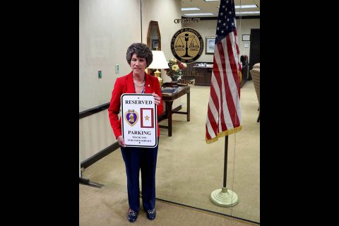 Clarksville Mayor Kim McMillan holds up one of the new reserved parking for Purple Heart recipients and Gold Star families signs.