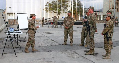 Sergeant Crystal Falcon (left), the support operations transportation contracting officer representative for the 101st Resolute Support Sustainment Brigade, speaks to her audience, instructing them on the proper way to determine the grid coordinates of a point on a military map, at Bagram Airfield, Afghanistan, Sept. 27, 2018. (SSG Caitlyn Byrne, 101st Sustainment Brigade PAO) 