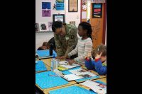 Spc. Morgan T. Henry, a medic assigned to Headquarters Company, 1st Battalion, 187th Infantry Regiment, 3rd Brigade Combat Team, 101st Airborne Division (Air Assault) looks at a student’s art project during a visit to South Christian Elementary School Jan. 11. (1st Sgt. Jason Lyday)