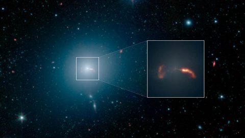 The galaxy M87, imaged here by NASA's Spitzer Space Telescope, is home to a supermassive black hole that spews two jets of material out into space at nearly the speed of light. The inset shows a close-up view of the shockwaves created by the two jets. (NASA/JPL-Caltech/IPAC)