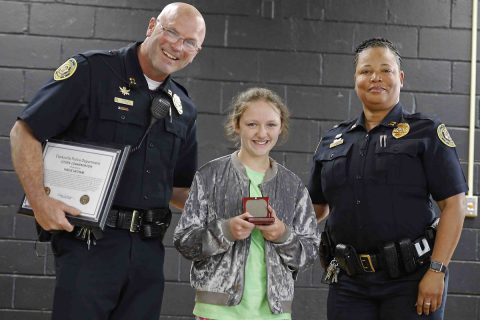 Clarksville Police Department's (L) Captain James Smith and (R) Captain Liane Wilson congratulate (M) Hailie Latham in front of her classmates.