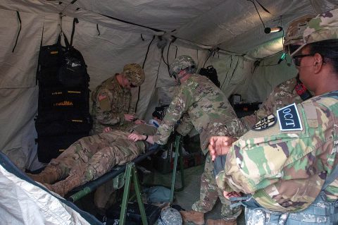 Pvt. Hunter Rodgers, a medic, and Capt. Chris Whittaker, a physician’s assistant, both assigned to 501st Area Support Medical Company based out of Fort Campbell, Kentucky, treat simulated patient, Pvt. Cameron Herring, while Observer Coach/Trainer Capt. Marjorie Attimy-Kalevela, a dentist with 7303rd Medical Training Support Battalion from Fort Gordon Georgia, observes the training as part of Guardian Response 2019 at Muscatatuck Urban Training Center, Indiana, May 1st, 2019. (Staff Sgt. Eric W. Jones, Army Reserve Medical Command)