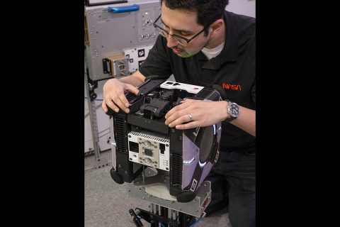 Astrobee robots are equipped with payload bays to support the installation and testing of new hardware. Jose Cortez, aerospace engineer at NASA’s Ames Research Center in Silicon Valley, checks the fit of a robot arm that locks into the top bay. The arm can be used to “perch” on one of many handrails in the International Space Station in order to conserve power while performing other operations, such as capturing video. (NASA's Ames Research Center/Dominic Hart)