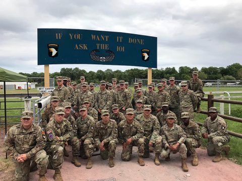 Soldiers assigned to the 101st Airborne Division (Air Assault) pose for a photo before a sign bearing the division’s motto “If you want it done, ask the 101,” June 2, 2019 in Carentan, Normandy, France. 