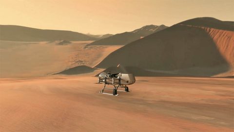 This illustration shows NASA’s Dragonfly rotorcraft-lander approaching a site on Saturn’s exotic moon, Titan. Taking advantage of Titan’s dense atmosphere and low gravity, Dragonfly will explore dozens of locations across the icy world, sampling and measuring the compositions of Titan's organic surface materials to characterize the habitability of Titan’s environment and investigate the progression of prebiotic chemistry. (NASA/JHU-APL) This illustration shows NASA’s Dragonfly rotorcraft-lander approaching a site on Saturn’s exotic moon, Titan. Taking advantage of Titan’s dense atmosphere and low gravity, Dragonfly will explore dozens of locations across the icy world, sampling and measuring the compositions of Titan's organic surface materials to characterize the habitability of Titan’s environment and investigate the progression of prebiotic chemistry. (NASA/JHU-APL)